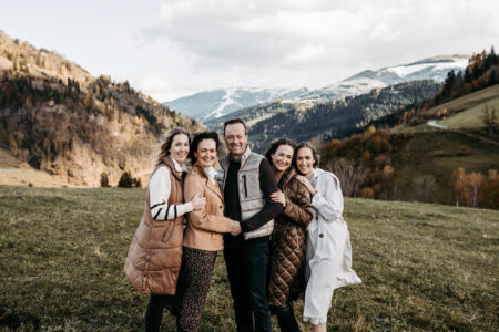 Fünfköpfige Familie posiert herzlich umarmt vor beeindruckender Bergpanorama in den Salzburger Alpen, herbstliches Familienportrait in der Natur, Familienfotografie Salzburg von Leonie Unterkofler